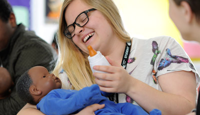Student feeding a practice baby